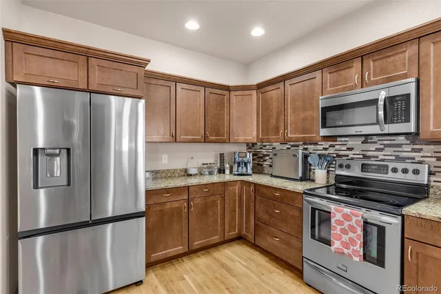 a kitchen with stainless steel appliances granite countertop a refrigerator stove a sink and dishwasher with wooden cabinet