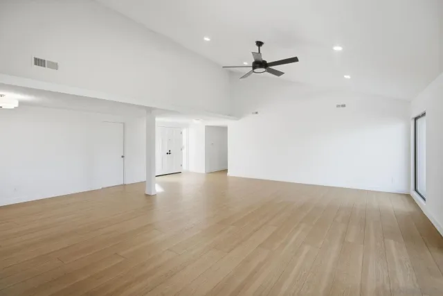 a view of empty room with wooden floor and fan
