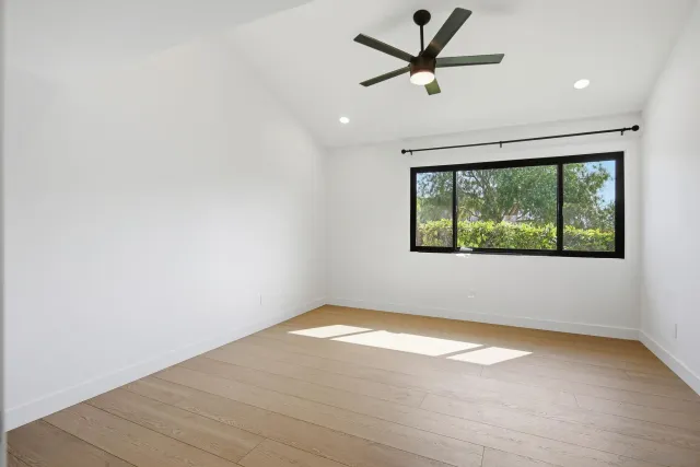 an empty room with a window and ceiling fan