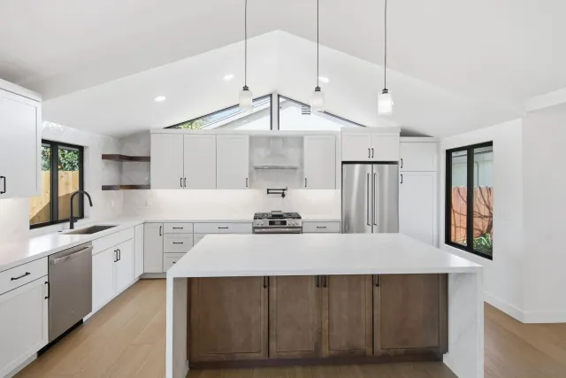 a kitchen with stainless steel appliances a refrigerator a sink and white cabinets
