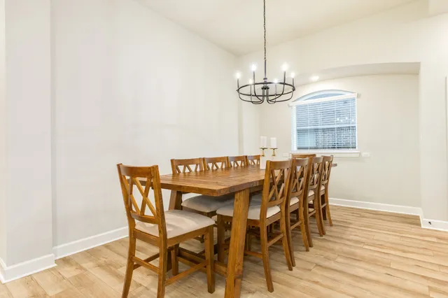 a view of a dining room and livingroom with furniture wooden floor a rug a chandelier