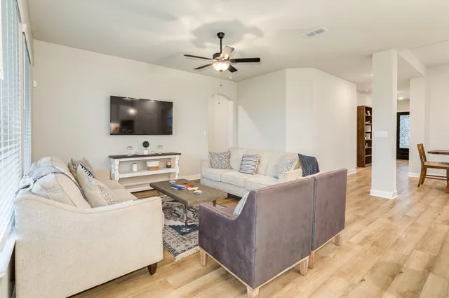a living room with furniture kitchen view and a large window