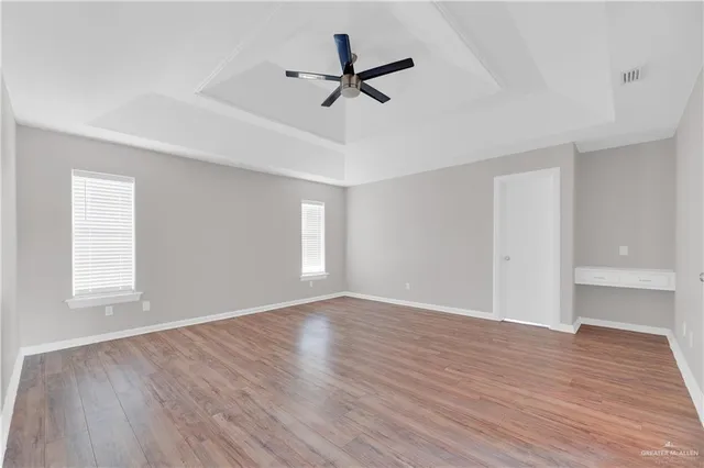 a view of a room with wooden floor and a ceiling fan