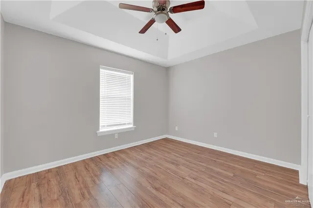 a view of empty room with wooden floor and fan