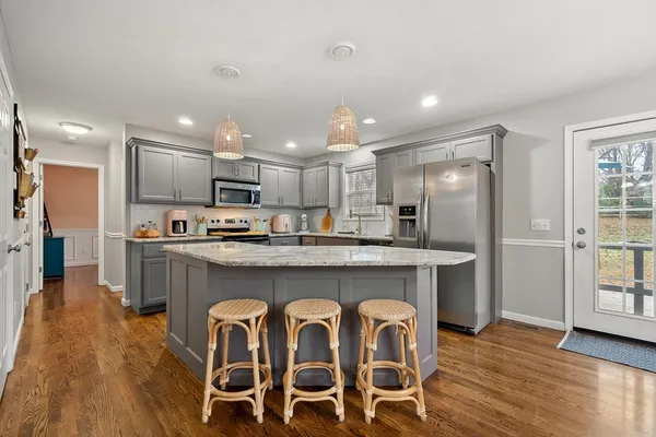 a kitchen with granite countertop a wooden floor and stainless steel appliances