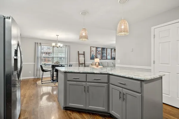 a kitchen with center island wooden floor and a refrigerator