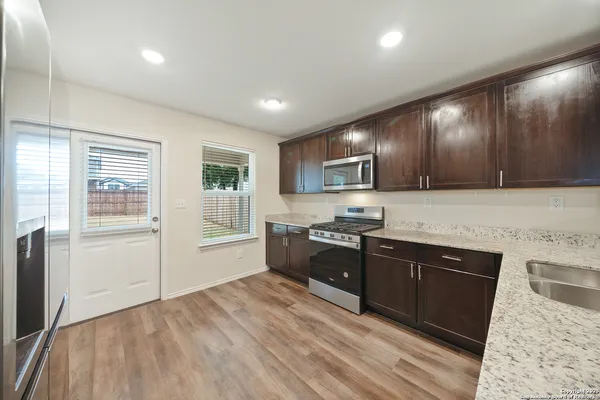 a large kitchen with wooden floors and stainless steel appliances