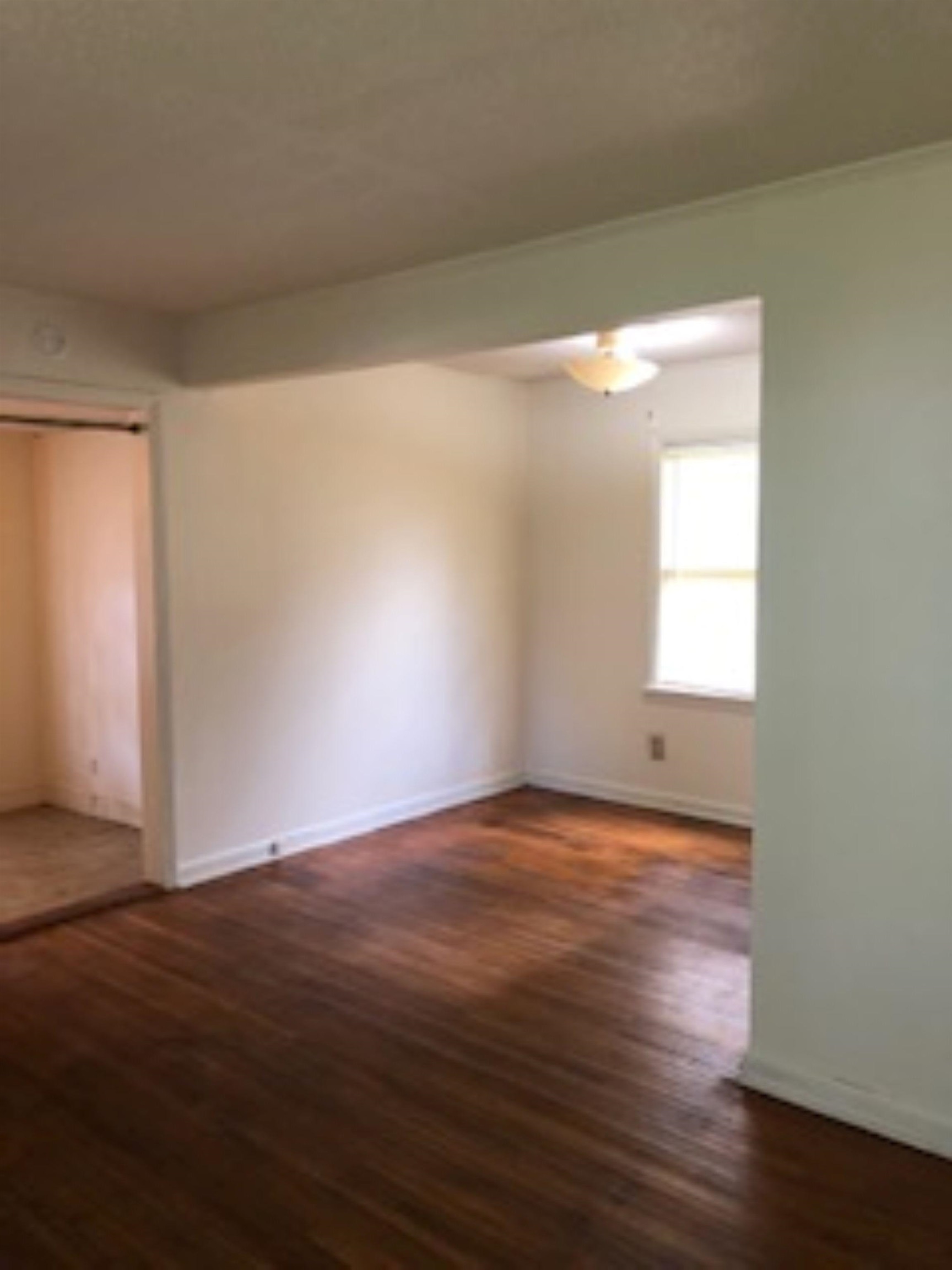 1048 Avon Road Memphis, TN 38122 - Photo 3 of 10 a view of an empty room with wooden floor and a window