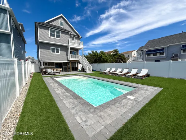 a view of a house with swimming pool lawn chairs and a yard