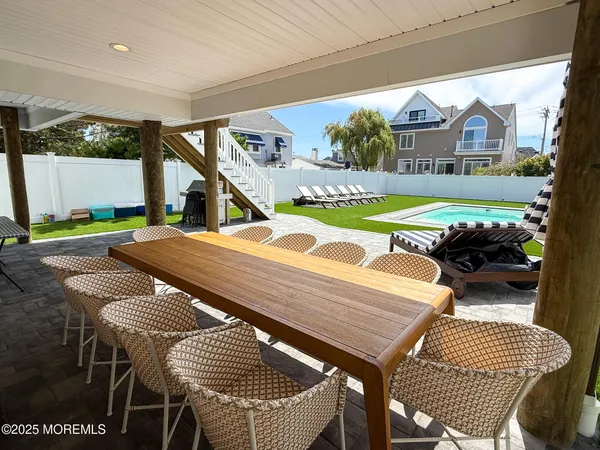 a view of a patio with table and chairs with wooden floor and fence