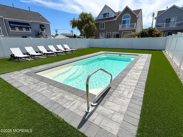 a view of swimming pool with lawn chairs and plants