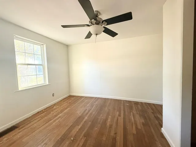 an empty room with a window and a ceiling fan