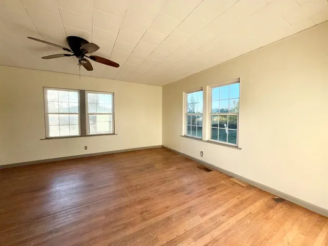 a view of an empty room with a window and wooden floor