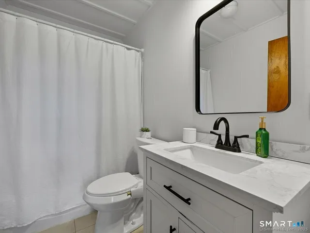 a bathroom with a granite countertop sink vanity mirror and toilet