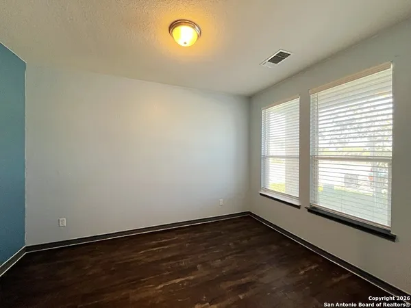 an empty room with wooden floor and windows