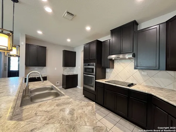 a kitchen with kitchen island stainless steel appliances a sink refrigerator stove microwave and cabinets