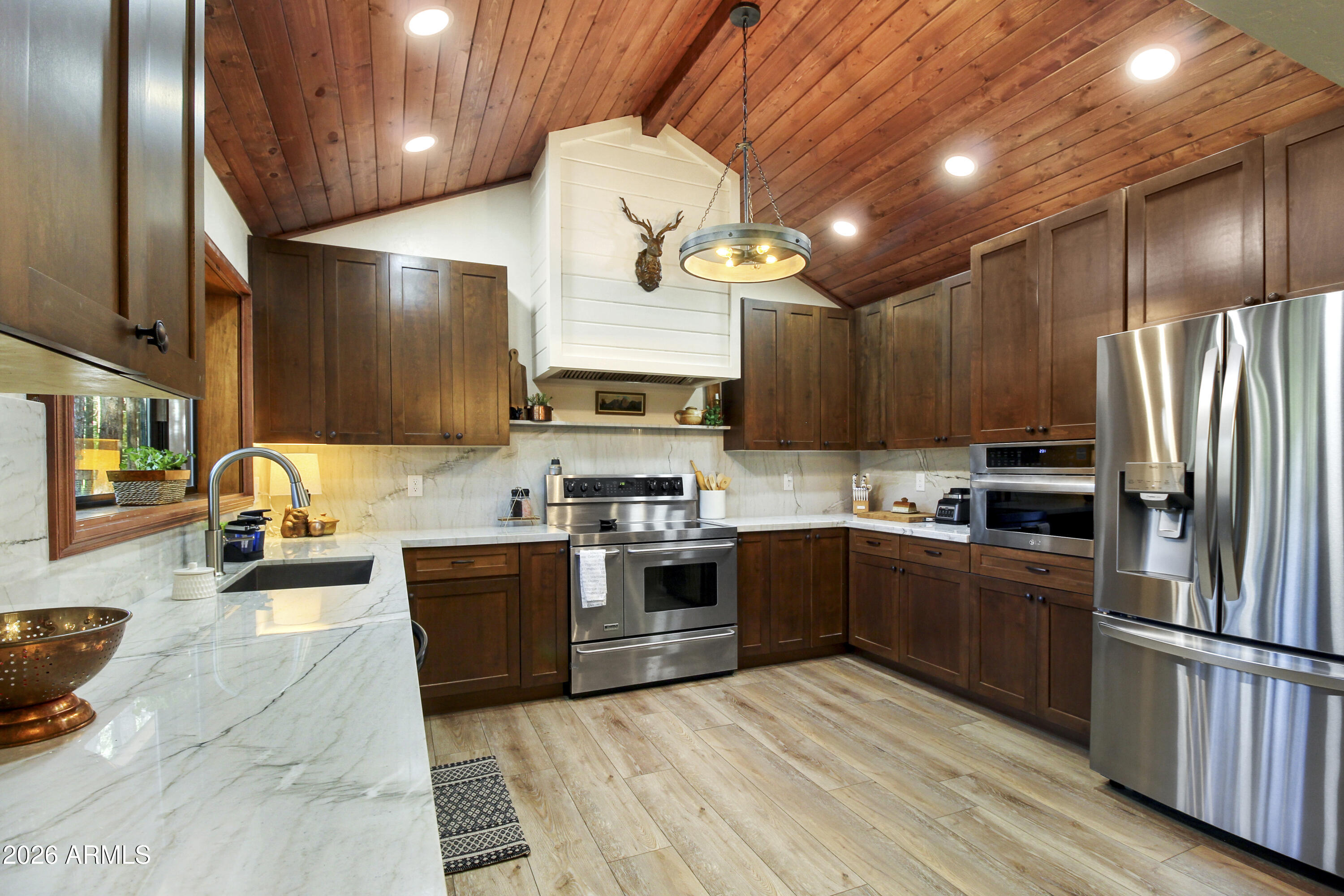 7414 Geronimo Road Pinetop, AZ 85935 - Photo 19 of 67 a large kitchen with stainless steel appliances lots of counter space and wooden floor