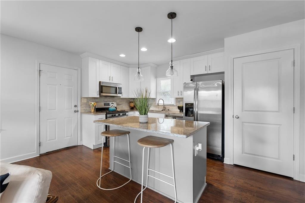 2474 Habersham Drive Decatur, GA 30032 - Photo 1 of 1 a kitchen with kitchen island a refrigerator a stove a sink and a dining table with wooden floor