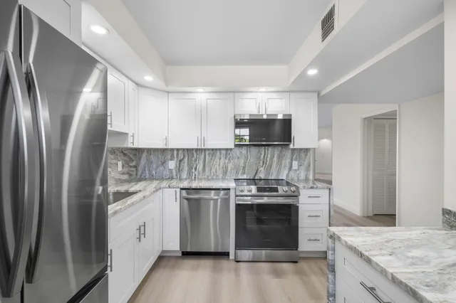 a kitchen with stainless steel appliances granite countertop a stove top oven a sink and a microwave