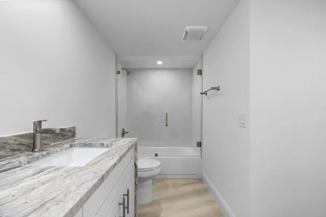 a bathroom with a granite countertop sink a toilet and shower
