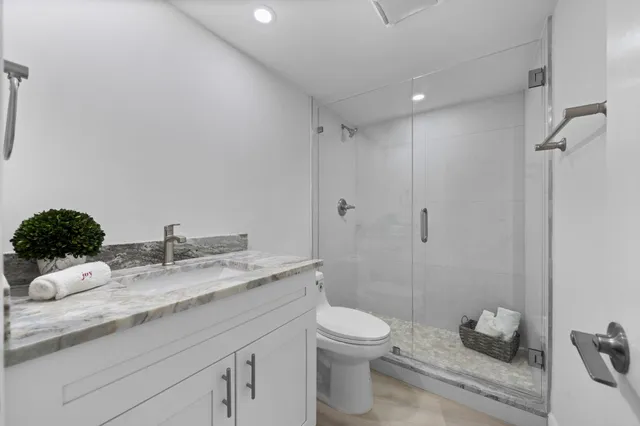 a bathroom with a granite countertop sink a toilet and a shower