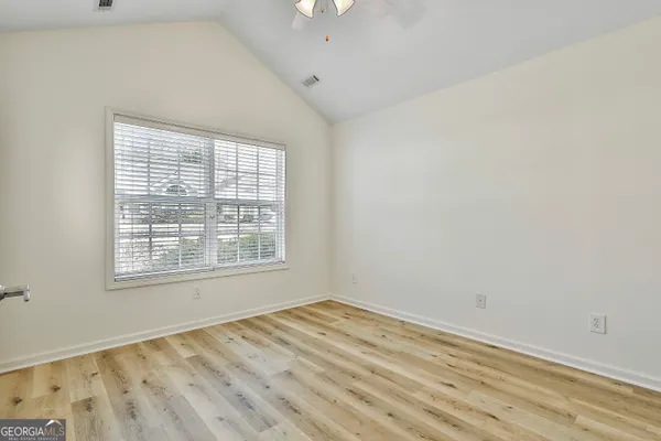 an empty room with wooden floor and windows