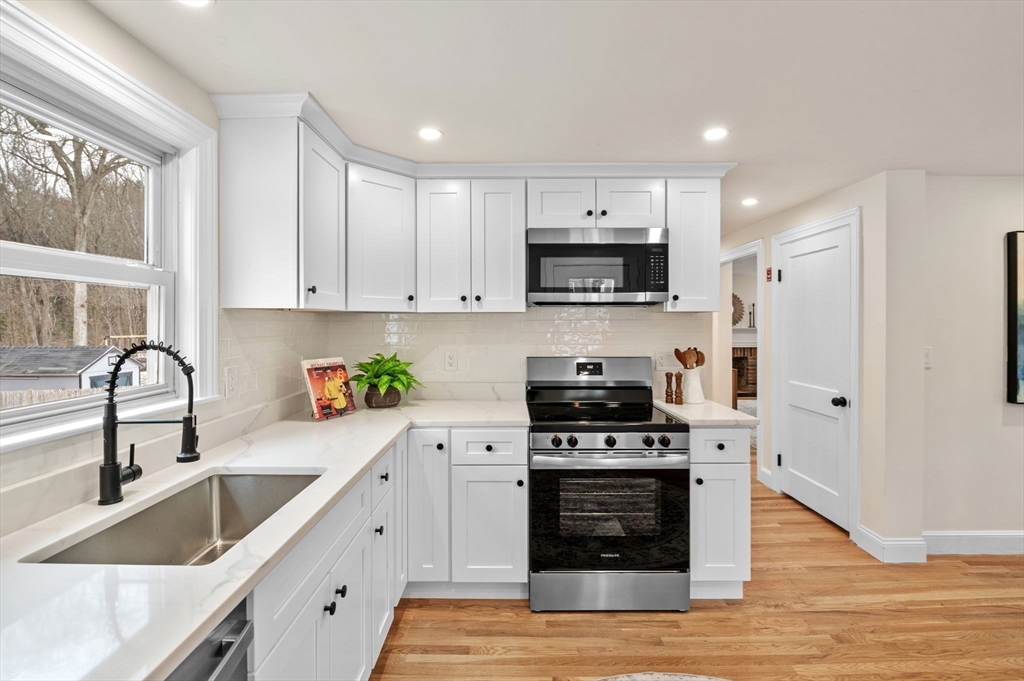 98 John Carver Road Reading, MA 01867 - Photo 3 of 40 a kitchen with stainless steel appliances a stove a sink a microwave and wooden cabinets