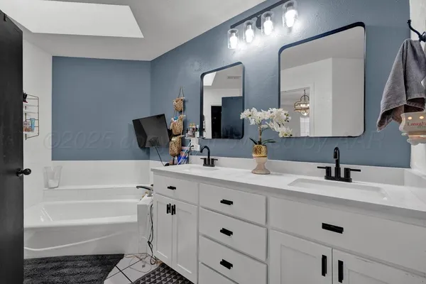 a bathroom with a double vanity sink mirror and bathtub
