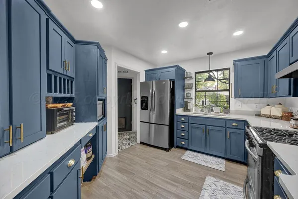 a kitchen with stainless steel appliances granite countertop a refrigerator a oven a sink dishwasher and wooden cabinets with wooden floor