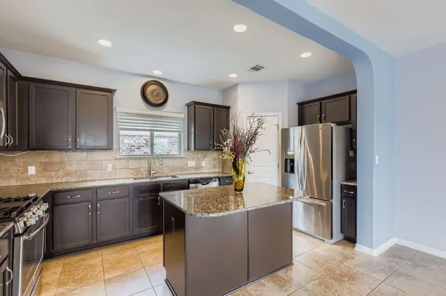 a kitchen with stainless steel appliances granite countertop a refrigerator a sink and a stove