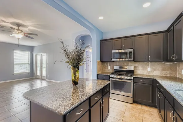 a kitchen with stainless steel appliances granite countertop a sink dishwasher stove and microwave with wooden floor