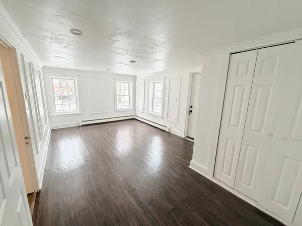 an empty room with wooden floor and windows