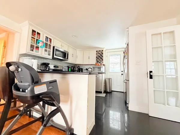 a living room with stainless steel appliances furniture a rug and a view of kitchen