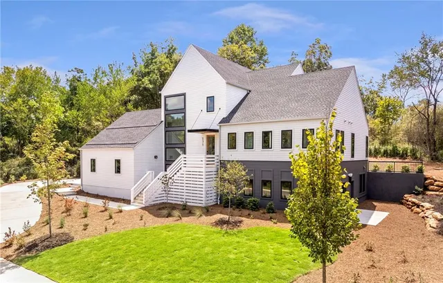 a view of a house with a small yard and a large tree