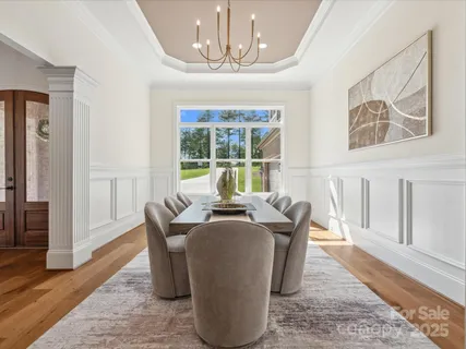 a dining room with chandelier and wooden floor