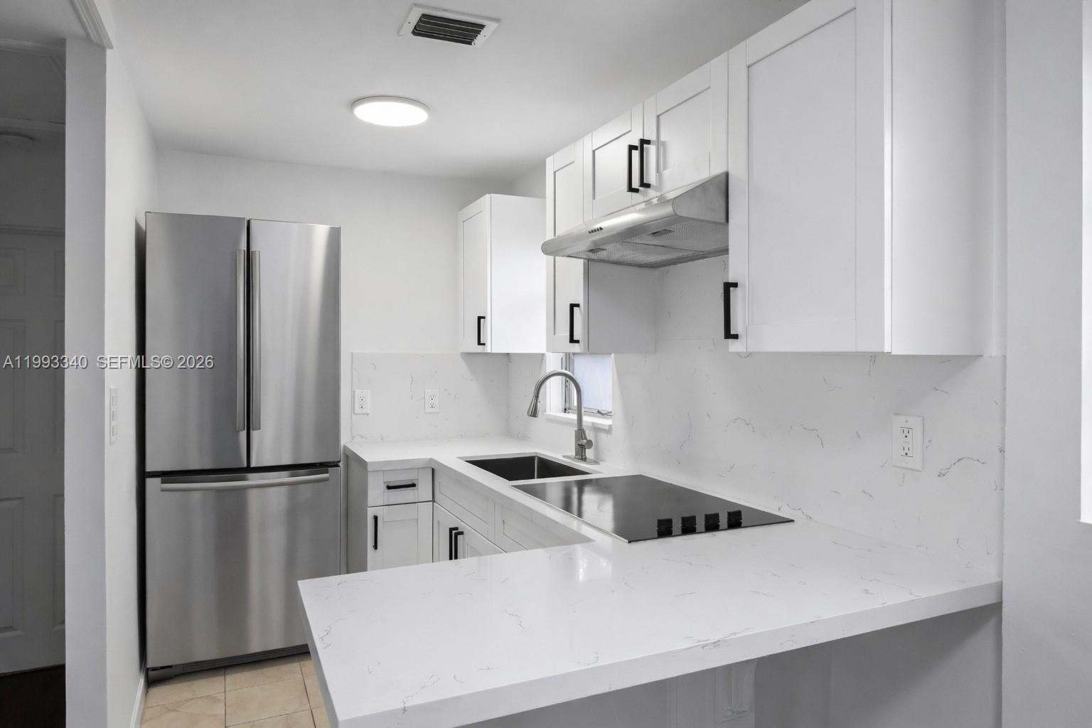 1408 Southwest 19th Terrace, Unit 1406 Miami, FL 33145 - Photo 5 of 12 a kitchen with stainless steel appliances a sink a refrigerator and cabinets
