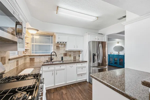 a kitchen with granite countertop a sink stove and refrigerator