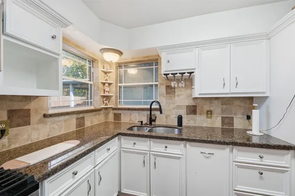 a kitchen with granite countertop white cabinets and white stainless steel appliances