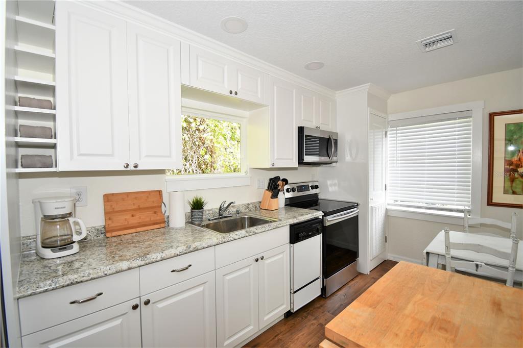 1245 Alexander Street Mount Dora, FL 32757 - Photo 41 of 55 a kitchen with granite countertop a sink a stove and cabinets