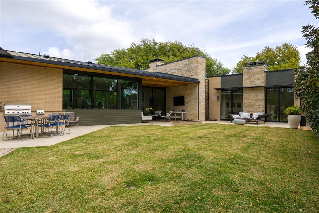 5736 Stonegate Road Dallas, TX 75209 - Photo 28 of 29 Expansive lawn area with multiple patio spaces, built-in outdoor grilling station, full-height windows, and stone architectural accents