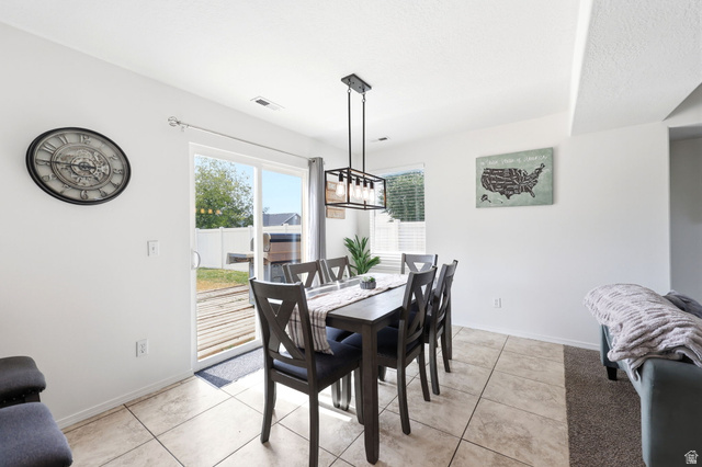 5485 Heather Way Tooele, UT 84074 - Photo 17 of 41 Dining area featuring tile flooring, a contemporary linear chandelier, and a sliding glass door providing outdoor access to a wooden deck