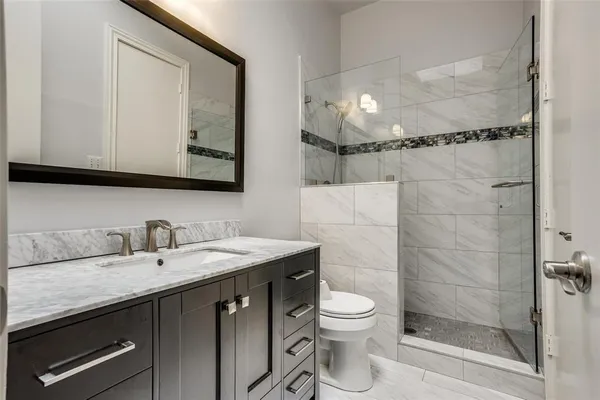 a bathroom with a granite countertop sink a mirror and a shower