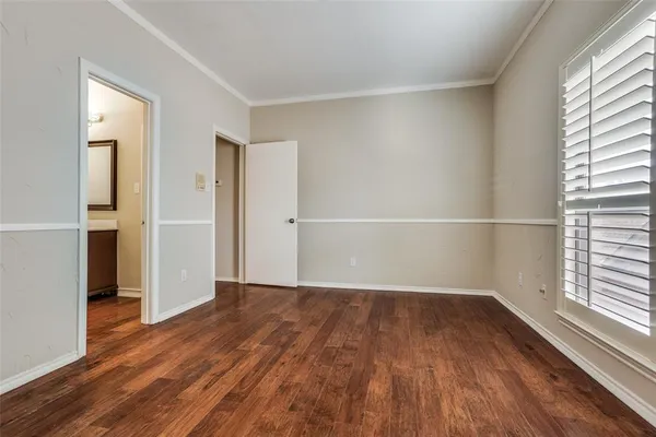 an empty room with wooden floor closet and windows