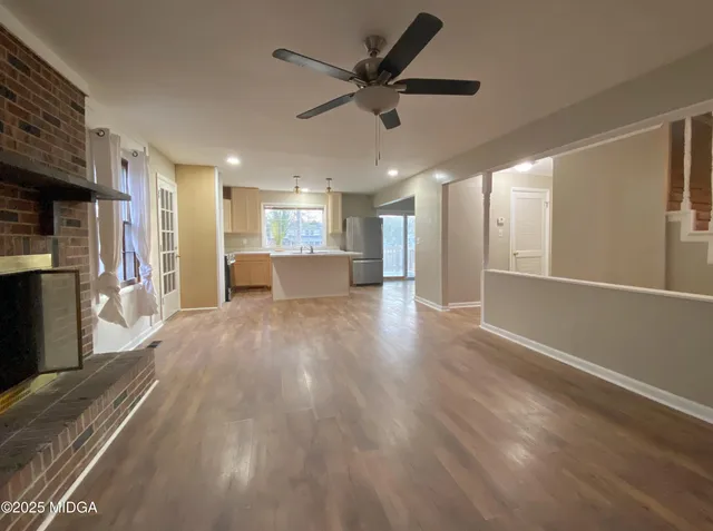 a view of a big room with wooden floor a ceiling fan and windows