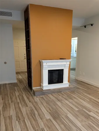 a view of an empty room with wooden floor and a fireplace