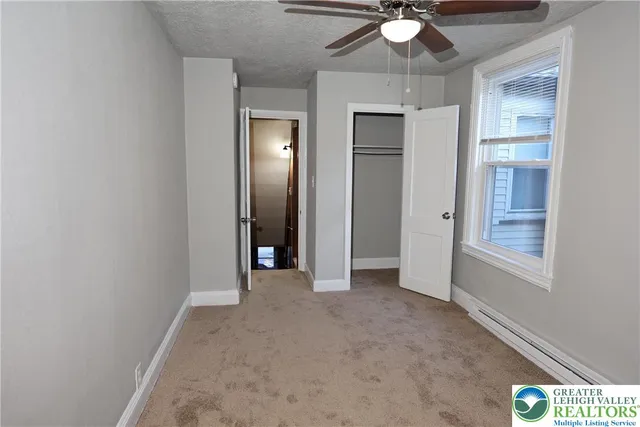 an empty room with chandelier fan and windows