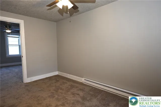 an empty room with a chandelier fan and windows