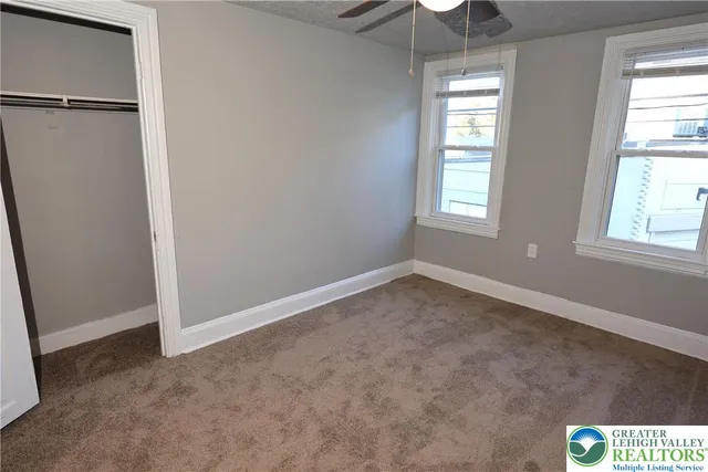 an empty room with windows and chandelier fan