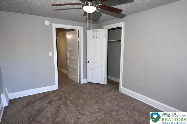 an empty room with a chandelier fan and a bathroom