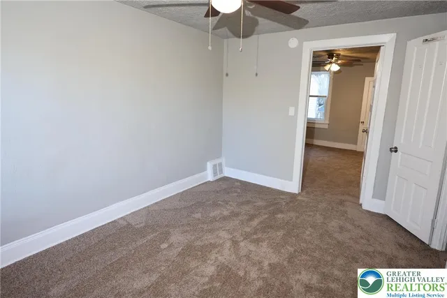 an empty room with a chandelier fan and closet